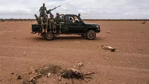 A vehicle with Somali National Army soldiers passes a group of goat carcasses lie on ground formerly used for pasture by local herders on October 17,2022 near Doolow in the Gedo region of South West Somalia.