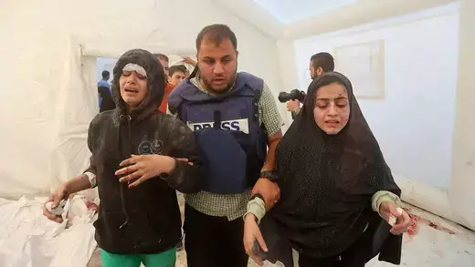 Press and children walk inside Al-Aqsa hospital