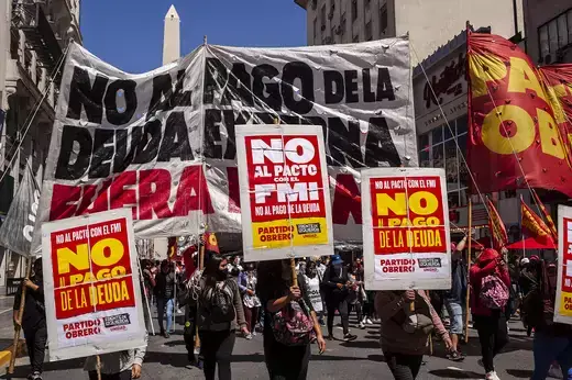 Demonstrators hold red and yellow signs protesting the IMF in Buenos Aires, Argentina.
