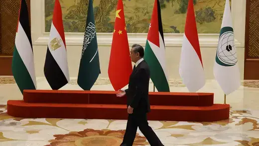 Chinese official walking across a row of flags from countries in the Middle East