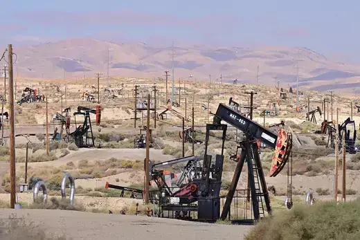 Oil machinery dots the foreground of a California desert landscape.