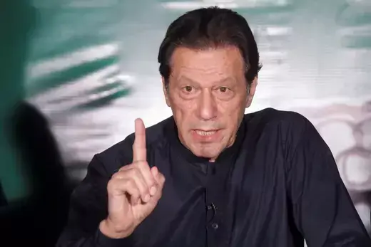 Former Pakistani Prime Minister Imran Khan wears a black tunic while speaking and waving his index finger.