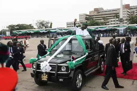 Nigeria's President Bola Tinubu waves to the crowd as he takes a drive on a top of a sports utility vehicle.