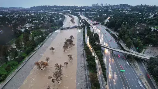 A brown river threatens to overflow alongside a highway.