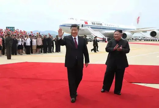 Chinese President Xi Jinping waves at photographers as North Korean Leader Kim Jong-Un claps at the Sunan International Airport in Pyongyang, North Korea.