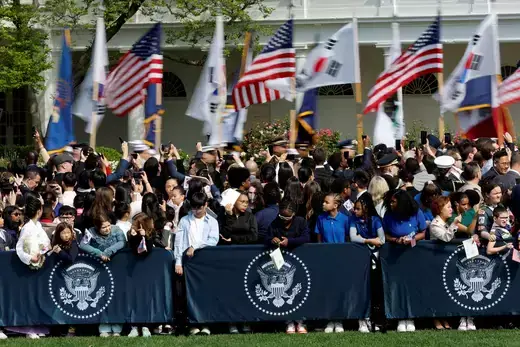 Military personnel carry U.S. and South Korean flags as people wait for an official state arrival ceremony for South Korean President Yoon Suk Yeol and First Lady Kim Keon Hee on the South Lawn of the White House on April 26, 2023. 