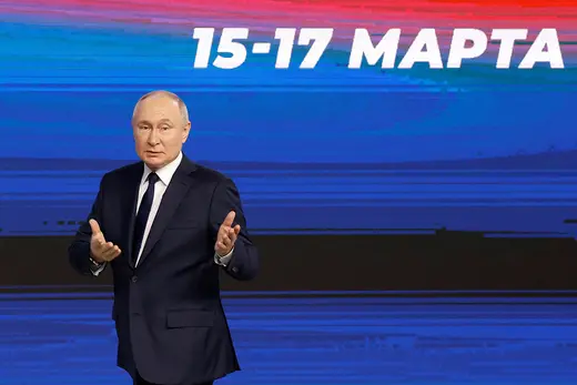 Russian President Vladimir Putin stands in front of a screen reading, "March 15-17."