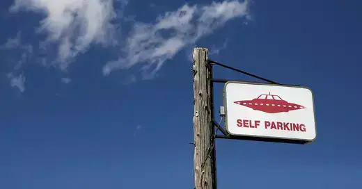 Sign for UFO "self parking" against a blue sky.