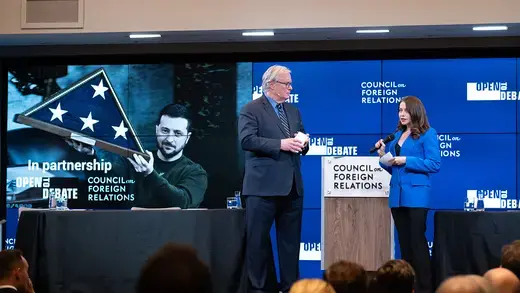 Presider and speaker of an Open to Debate event on the CFR stage with an image of Volodymyr Zelenskyy in the background