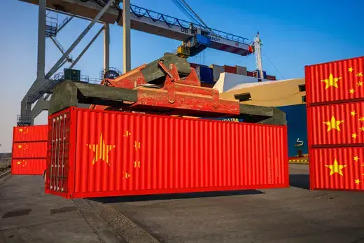 Chinese shipping containers being unloaded at a port.