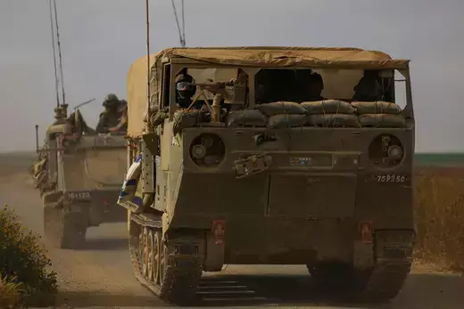 Two Israeli military vehicles as viewed driving on a road.