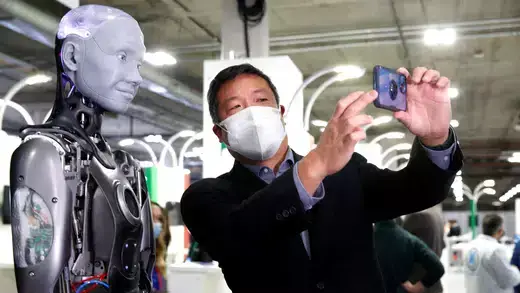 A man takes a selfie with Ameca, a humanoid robot. 