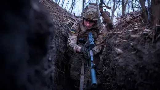 A Ukrainian sniper leads other troops through a trench during a training exercise