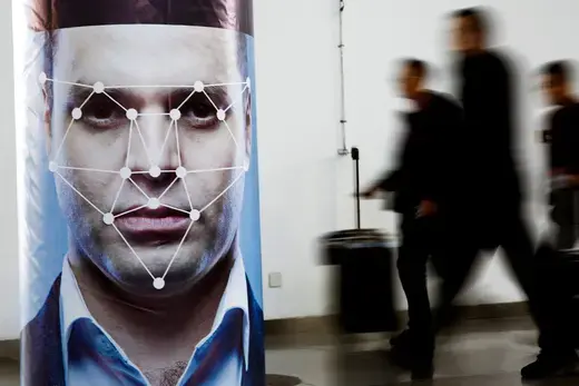 People walk past a poster simulating facial recognition software at the Security China 2018 exhibition on public safety and security in Beijing, China on October 24, 2018