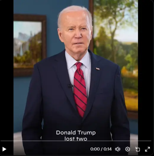 Biden as viewed standing wearing a navy suit and a red tie. 