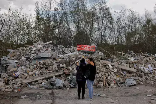 Two women react in front of a pile of rubble that is left of the cafe that hosted the wake and was hit by a Russian missile, following a Russian military strike, amid Russia's attack on Ukraine, in the village of Hroza, Kharkiv region, Ukraine October 6, 