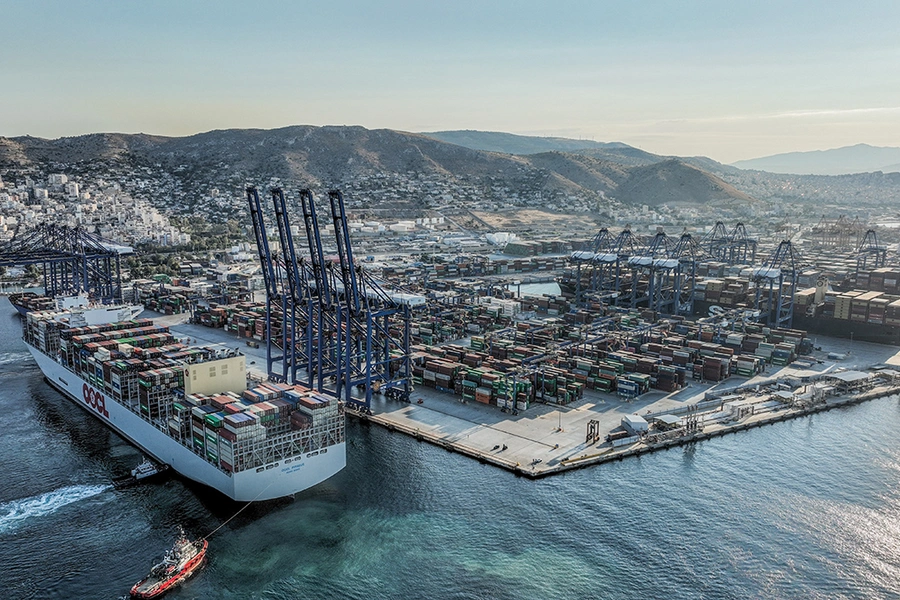 A massive, loaded container ship being tugged from a shipyard.