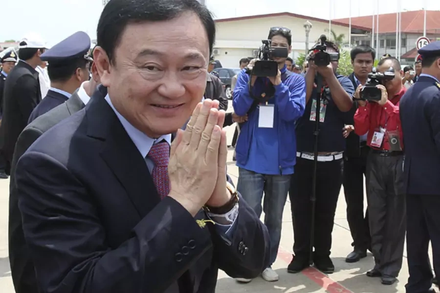 Former Thai prime minister Thaksin Shinawatra greets the media upon his arrival at the Siem Reap International Airport in Camb...premier Thaksin took some small but symbolic steps towards the fringes of his homeland on Wednesday after five years in exile.