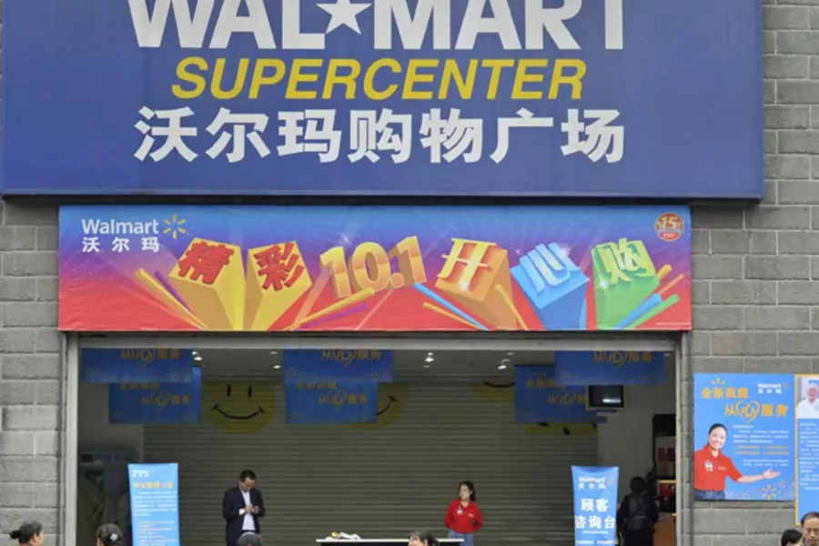 Employees stand in front of the gate to a Wal-Mart Supercenter in Chongqing municipality, China. (Stringer/Courtesy Reuters)