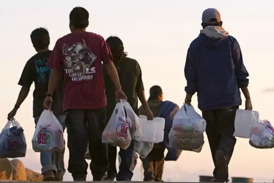 Migrant farm workers walk back to their camp with food and other supplies in San Diego