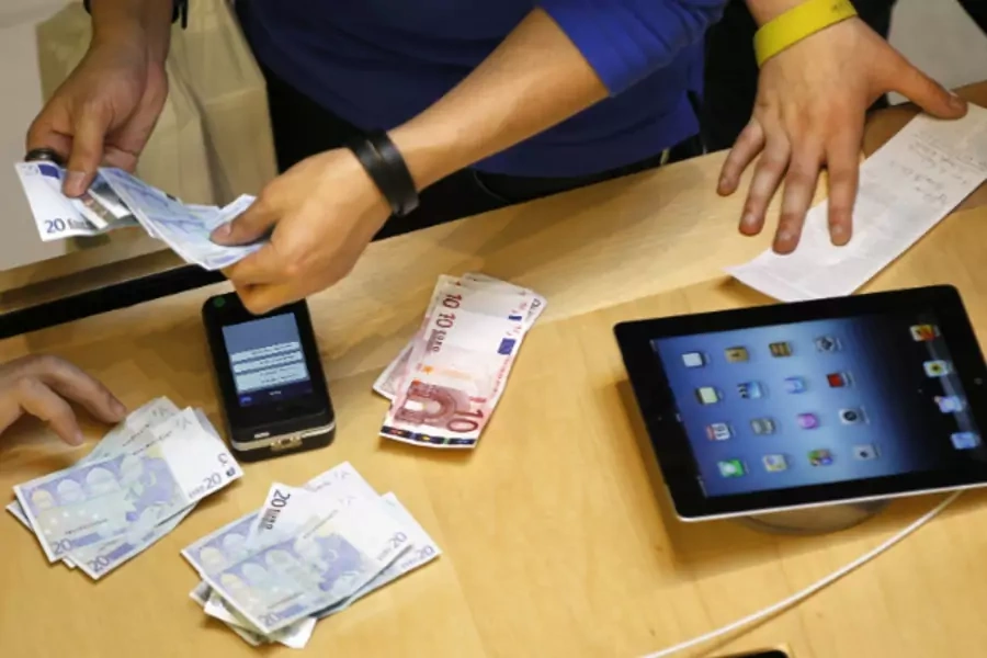 A cashier counts euro banknotes as a customer purchases an Apple iPad in Paris on March 16, 2012 (Charles Platiau/Courtesy Reuters).