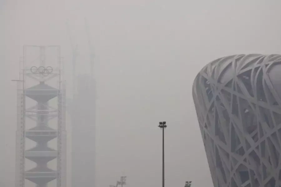 The National Stadium, also known as the 'Bird's Nest', can be seen next to a tower bearing the Olympic rings and a building under construction on a high air pollution day in Beijing on June 6, 2012.