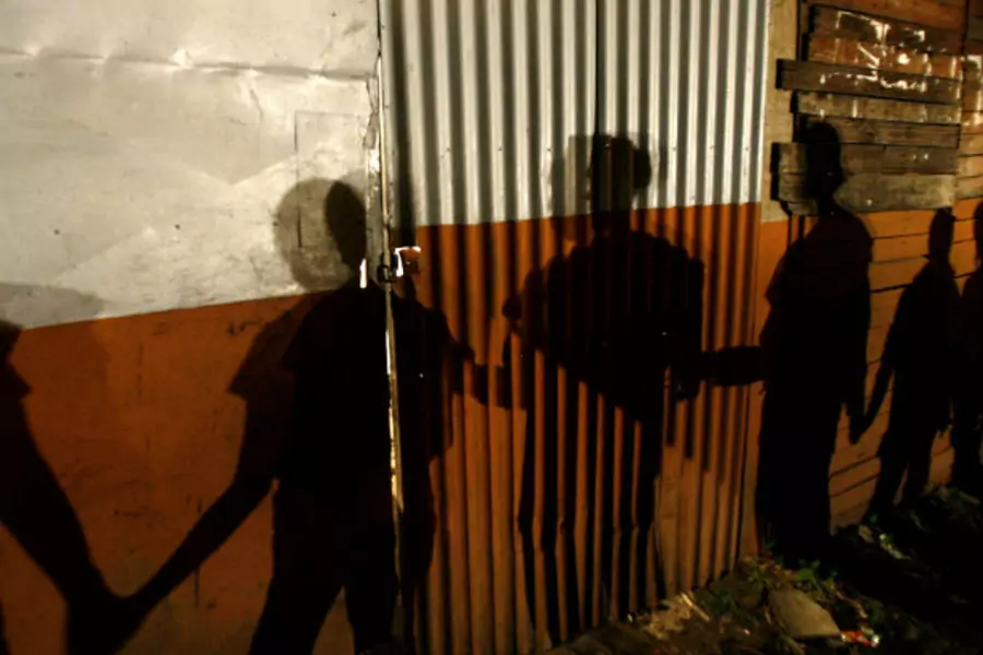 Shadows on a slum wall are cast by Nicaraguan immigrants to Costa Rica during a prayer session in the neighborhood of Triangulo de la Solidaridad