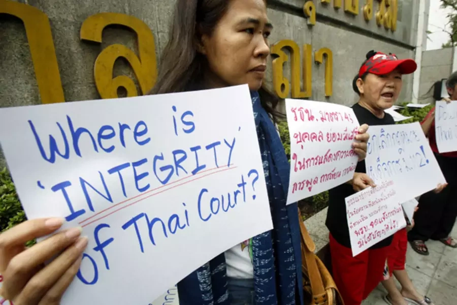 Activists hold signs as they gather in front of the Thai Criminal court during a protest in Bangkok January 25, 2013.