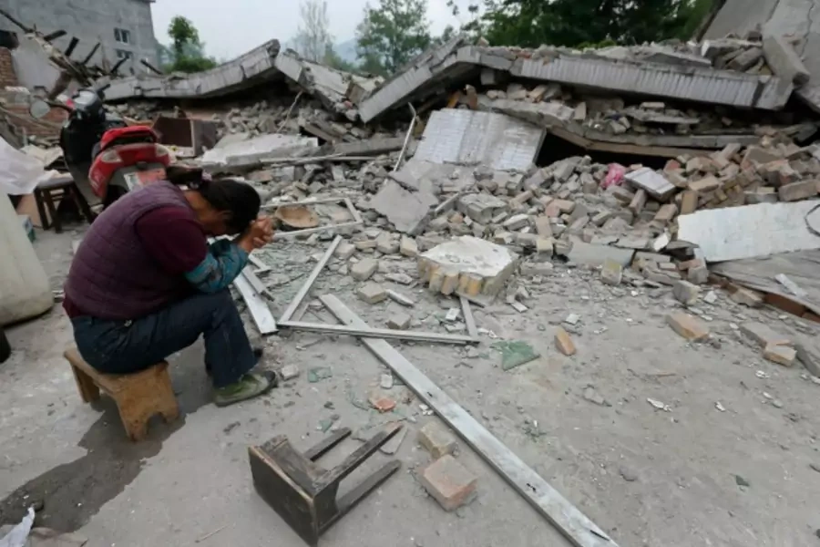 A woman sits with her head down next to a damaged house after Saturday's earthquake hit Lushan county, Ya'an, Sichuan province, on April 22, 2013.