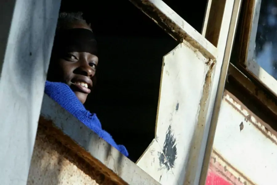 A Kenyan student looks through a broken window in a classroom in Nairobi, Kenya, January 2005 (Courtesy Reuters/Antony Njuguna).