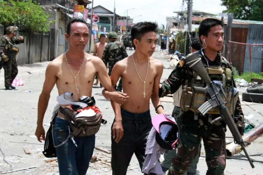Government soldiers escort residents who were taken hostage and used as human shields by Muslim rebels of Moro National Libera...ighting with government soldiers, in Zamboanga city in southern Philippines on September 17, 2013. (Stringer/Courtesy Reuters)
