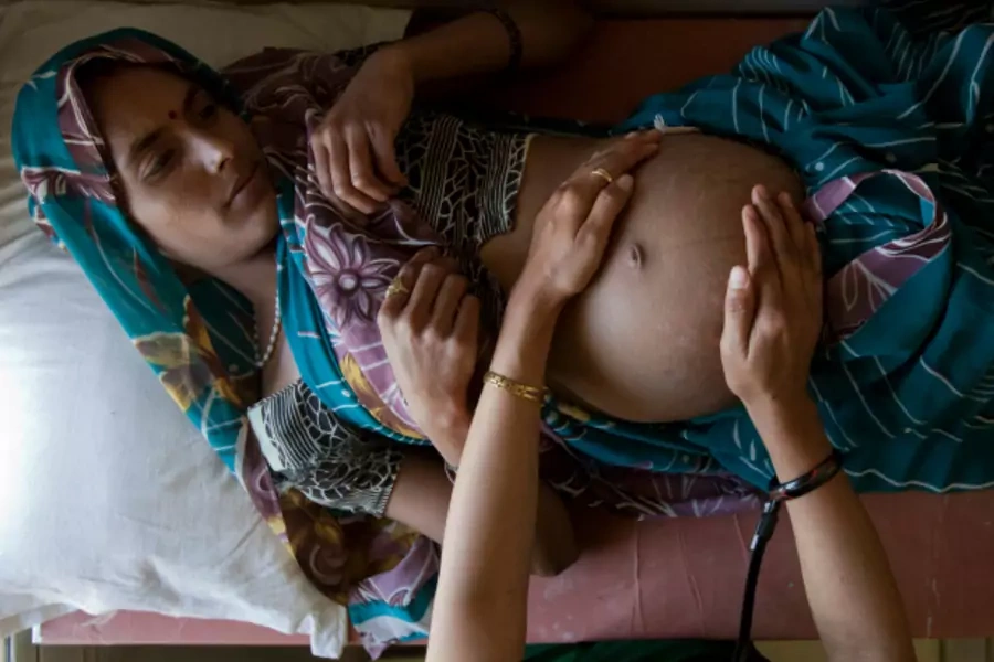 A pregnant woman lies on an examination table during a checkup at a community health center in the remote village of Chharchh, in the central Indian state of Madhya Pradesh, February 2012 (Courtesy Reuters/Vivek Prakash).