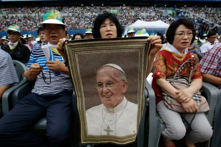 A woman holds a picture of Pope Francis while waiting for his arrival for the Holy Mass at Daejeon World Cup stadium in Daejeo...spiritual "cancer" that often accompanies affluent societies. REUTERS/Lee Jin-man/Pool (SOUTH KOREA - Tags: RELIGION POLITICS)