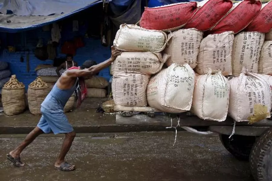 A labourer pushes a handcart loaded with sacks containing tea packets, towards a supply truck at a wholesale market in Kolkata...promises that finally got a goods and services tax (GST) bill before parliament, they have turned wary (Reuters/De Chowdhuri).