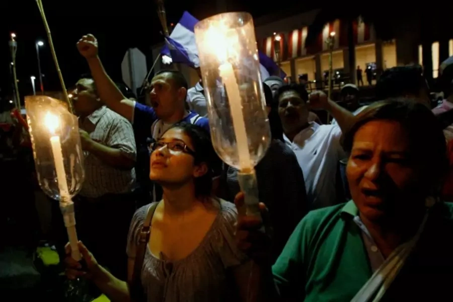 Demonstrators hold candles as they sing the national anthem during a march to demand the resignation of Honduras' President Ju...tion of Hernandez over a $200-million corruption scandal at the Honduran Institute of Social Security (Reuters/Jorge Cabrera).