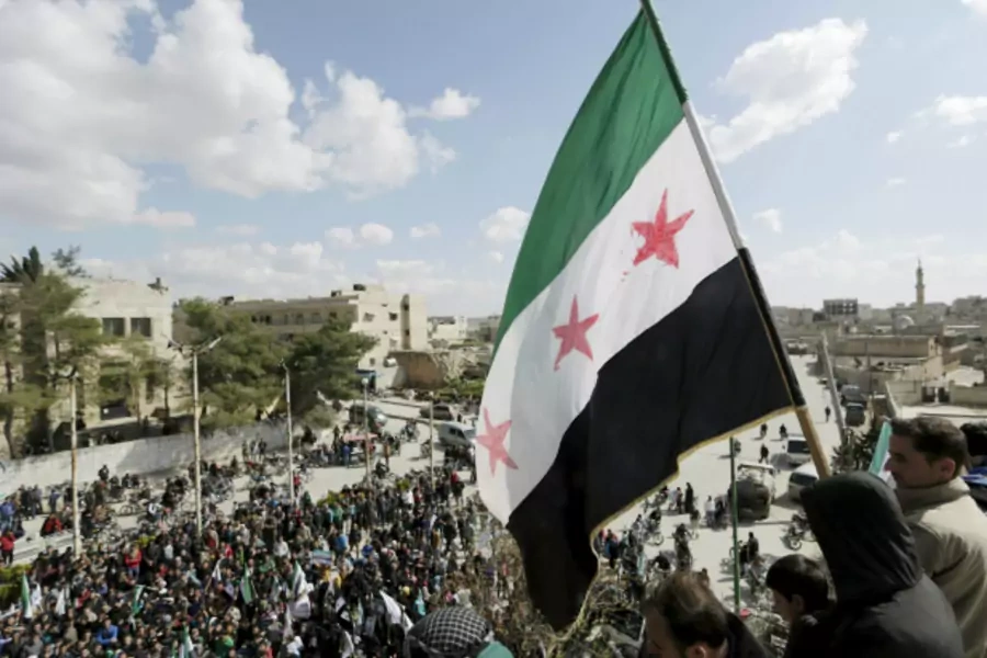 Men carry a Free Syrian Army flag while attending an anti-government protest in Maarat al-Numan, south of Idlib, Syria (Khalil Ashawi/Reuters).