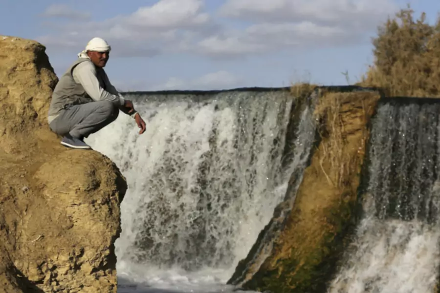 A man sits near the waterfall at Wadi El-Rayan in the Al Fayoum Governorate, southwest of Cairo, Egypt (Mohamed Abd El Ghany/Reuters).