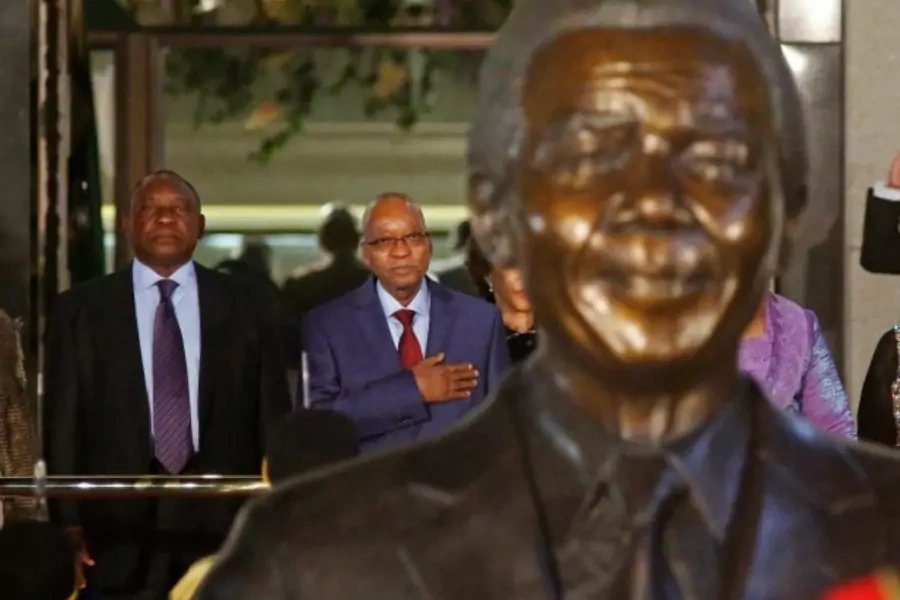 South African President Jacob Zuma (2nd L) stands behind a statue of former South African President Nelson Mandela outside Parliament in Cape Town, June 17, 2014.