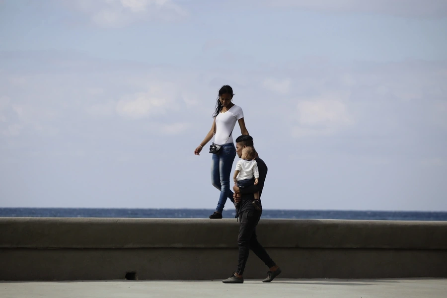 A young couple walks with their baby on Havana's El Malecon seafront bolulevard (March 28, 2013) 