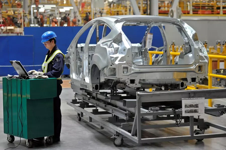 An employee uses a laptop next to a car body at an assembly line at a Ford manufacturing plant in Chongqing municipality April 20, 2012. 