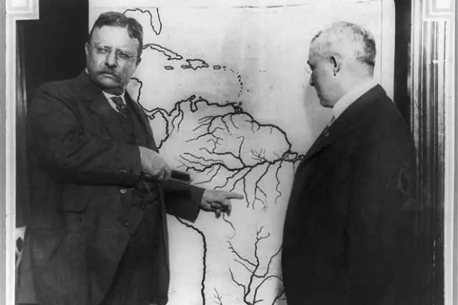 President Roosevelt pointing at a map of South America towards the area explored during the Roosevelt-Rondon Scientific Expedition in Brazil as another man looks on between 1913 and 1919.