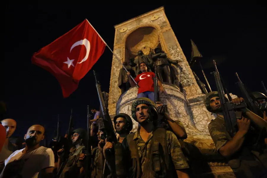 Turkish military stand guard near the the Taksim Square as people wave with Turkish flags in Istanbul (Murad Sezer/Reuters).