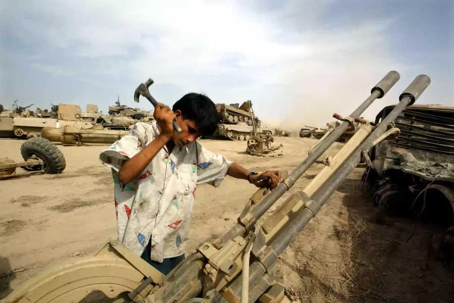 An Iraqi man recovers metal parts from an anti-aircraft gun in a wreckage dump on the outskirts of Baghdad (Jamal Saidi/Reuters).