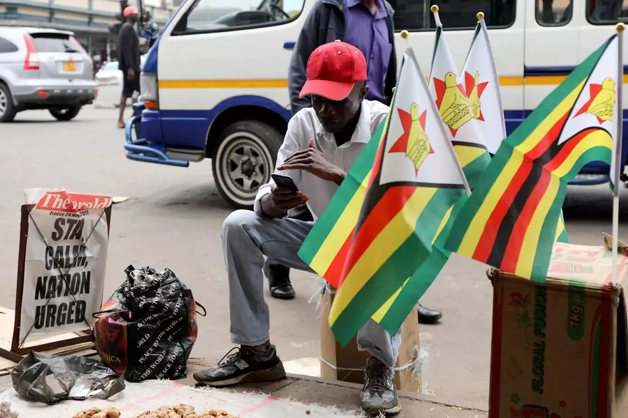 A street vendor watches Emmerson Mnangagwa's presidential inauguration ceremony on his mobile phone in Harare, Zimbabwe, November 24, 2017. 