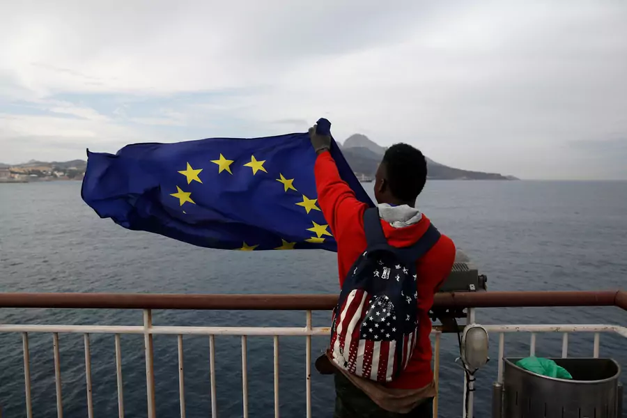 An African migrant holds a European Union flag on board a ferry to Algeciras after having awaited in CETI, the short-stay immigrant centre in Spain's north African enclave of Ceuta to be transferred to mainland Spain, February 23, 2017.