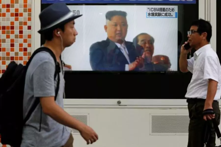Men walk past a street monitor showing North Korea's leader Kim Jong-Un in a news report about North Korea's nuclear test, in Tokyo, Japan, September 3, 2017.