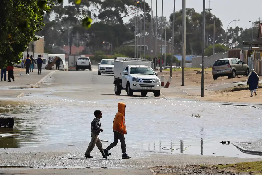 Children walk past a puddle after heavy rains in drought-hit Cape Town, South Africa, April 26, 2018. When it does rain, drought conditions increase the likelihood of flooding as dry, compacted soil is less able to absorb water.