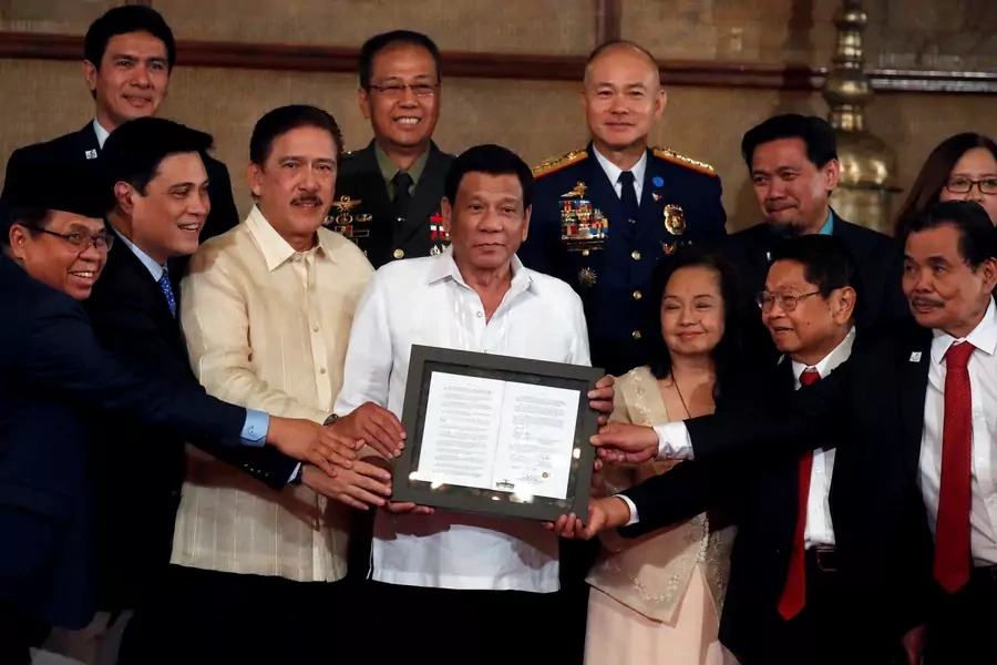 President Rodrigo Duterte, Moro Islamic Liberation Front chairman Murad Ebrahim, and other government and military officials show a document containing a signed autonomy law during a ceremony in Manila, Philippines on August 6, 2018.