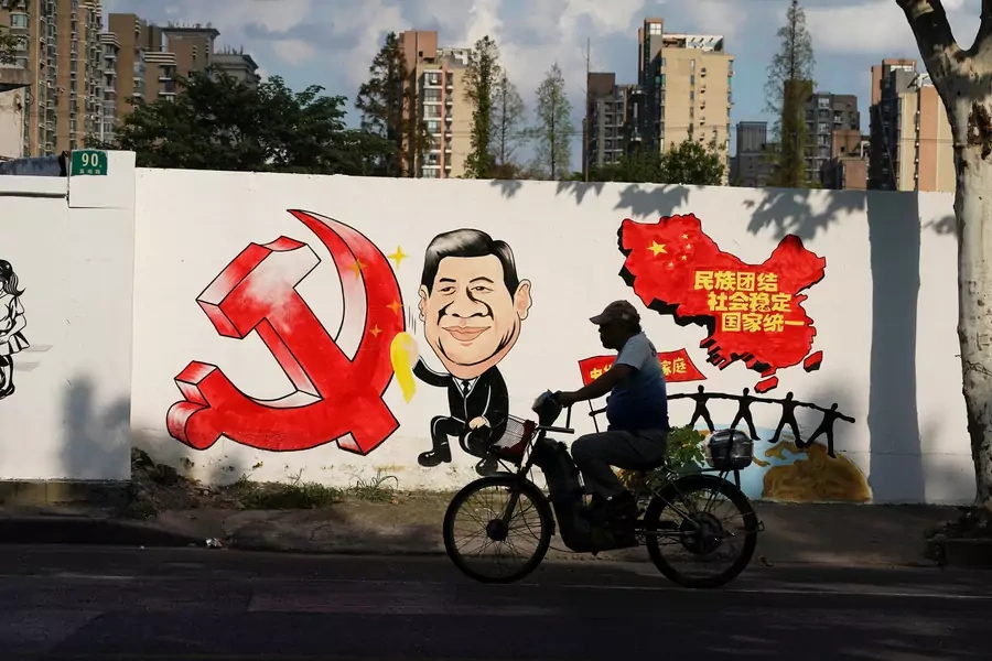 A man rides a bicycle next to a mural showing an image of Chinese President Xi Jinping along a street in Shanghai, China September 28, 2018. 