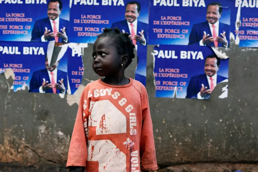 A girl stands near a wall covered with placards of Cameroon President Paul Biya, who was reelected two days later, in Yaounde, Cameroon, on October 5, 2018.